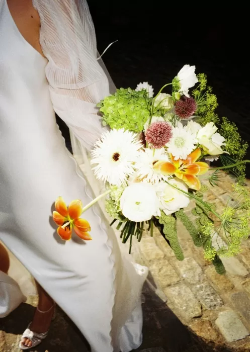 A radiant bridal bouquet with white gerberas and orange lilies, captured at Mas Torroella.