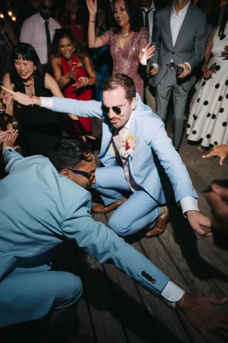 Energetic dance floor moment with the grooms surrounded by guests at Masia Casa del Mar.