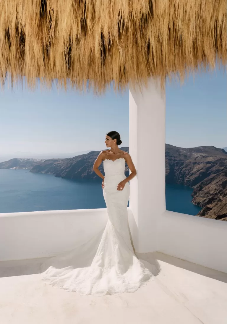 Bride poses atop a whitewashed rooftop hut, iconic of Rocabella Santorini’s Cycladic charm