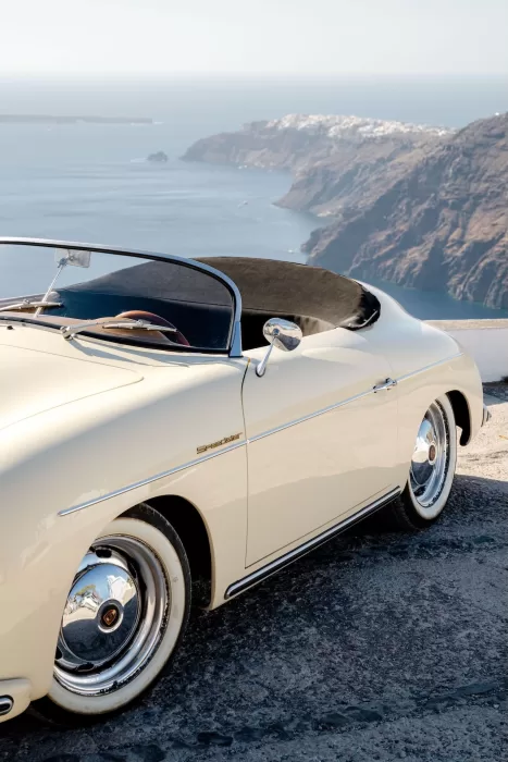 Cream vintage Speedster parked on a cliffside road overlooking the caldera at Rocabella Santorini.