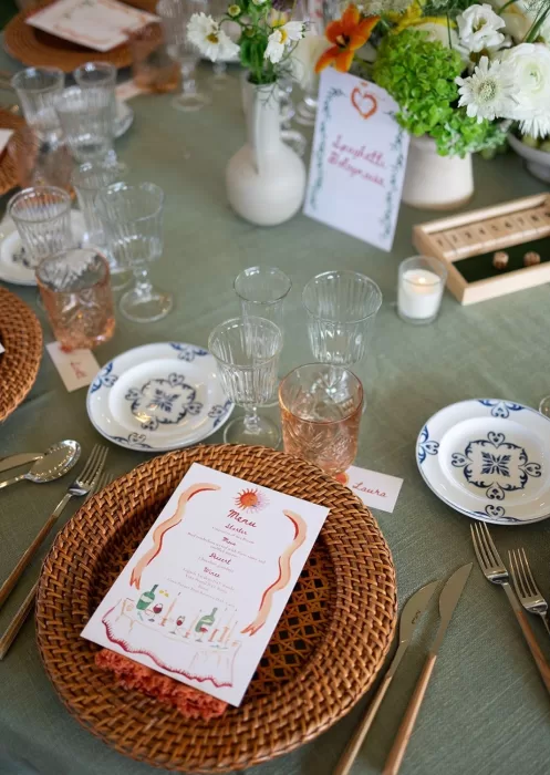 Table centerpiece of white ranunculus, green hydrangeas, and orange lilies, with a "Spaghetti Bolognese" table card