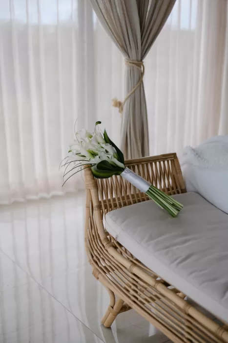 White calla lily bouquet resting on rattan lounger in sunlit bridal suite at Villa La Joya.