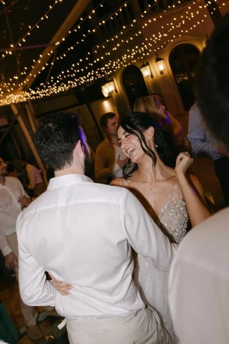 Bride laughing during a joyful dance under twinkling lights at Villa La Joya wedding reception.