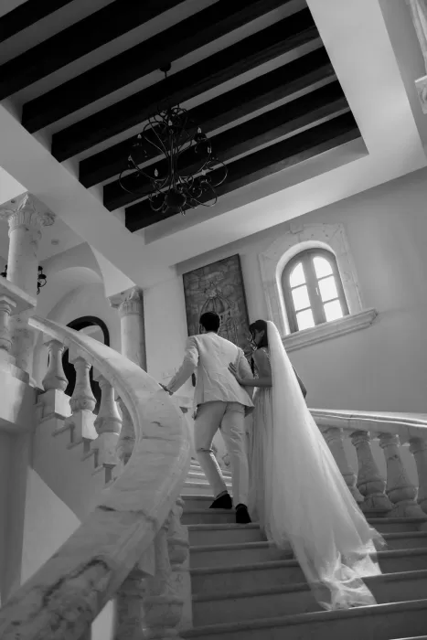 Couple ascending marble staircase inside Villa La Joya, wrapped in soft natural light.