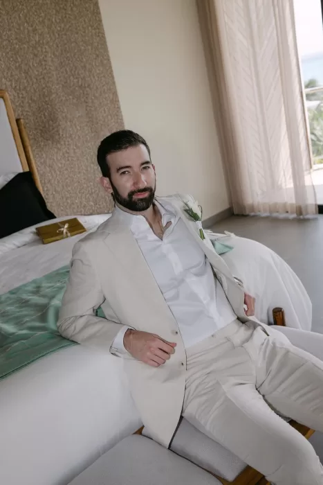 Groom relaxing in his suite before the ceremony at Villa La Joya, dressed in a cream linen suit.