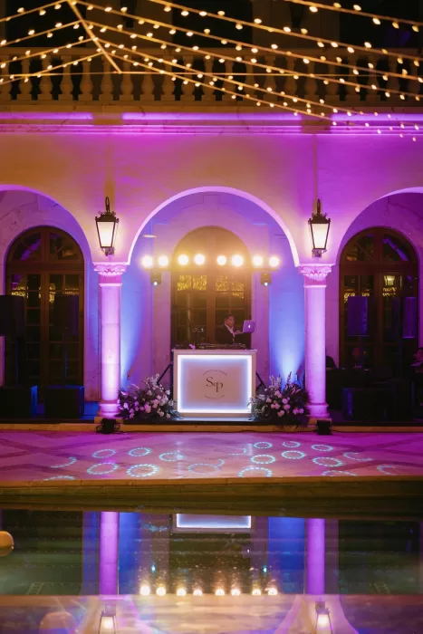 Nighttime wedding reception at Villa La Joya with vibrant uplighting, string lights, and DJ booth.