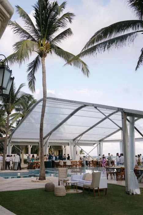 Elegant outdoor reception setup at Villa La Joya beneath a clear tent with palm trees and ocean views.