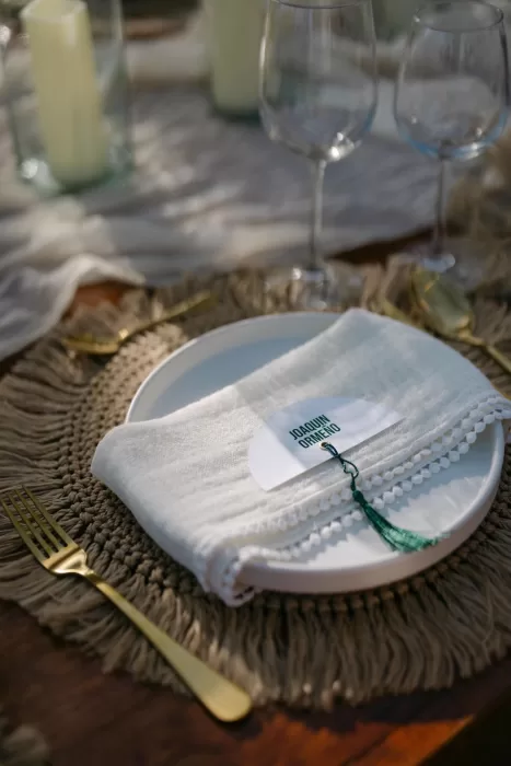 Chic tropical wedding table setting at Villa La Joya with woven placemats, white linens, and gold cutlery.