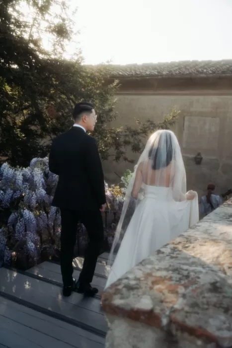 Bride and groom smiling together in front of blooming wisteria at Villa di Maiano.