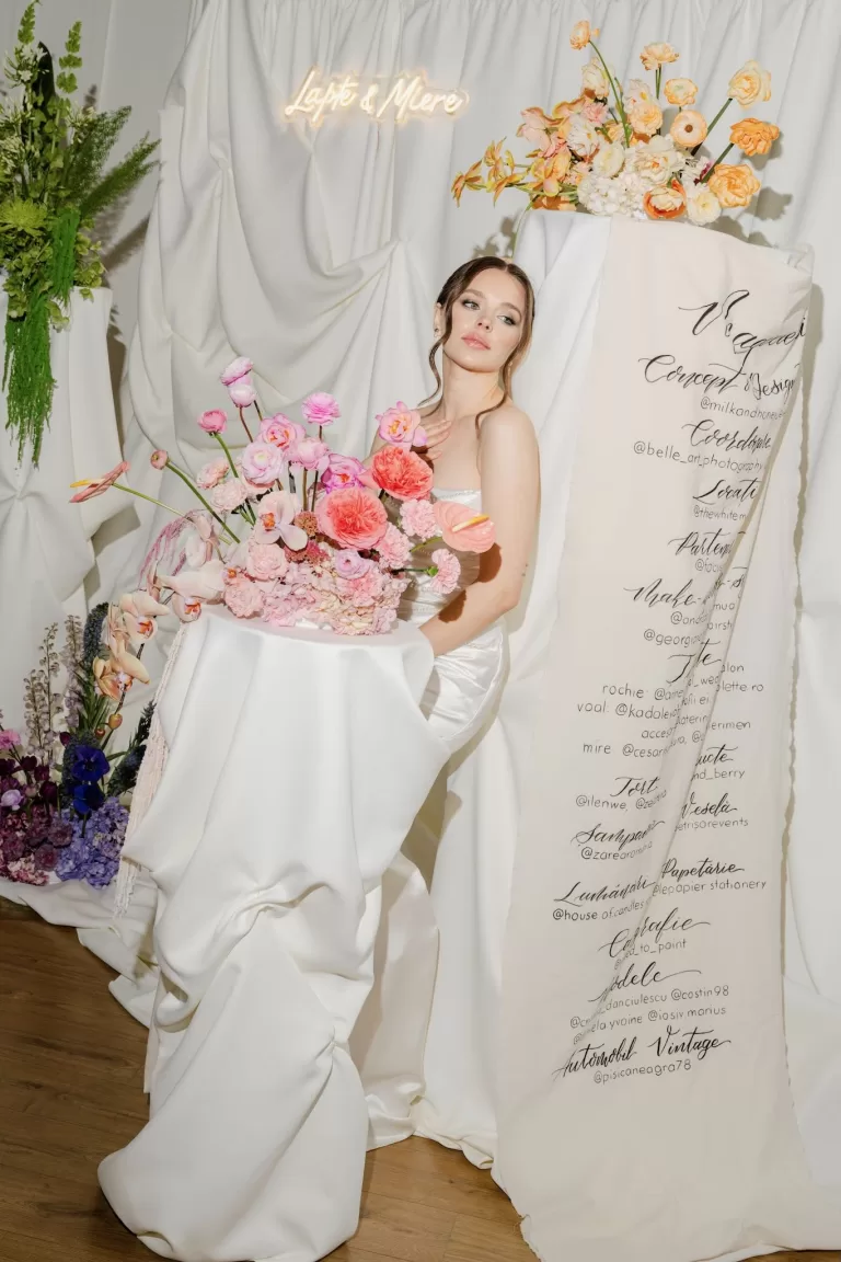 Full-length shot of a bride next to an elegant floral display with modern calligraphy decor.