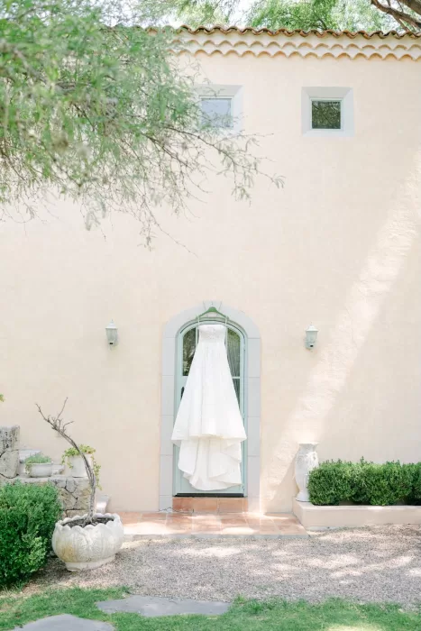 Wedding dress hanging on a soft peach stucco wall at Luna Escondida, ready for the ceremony