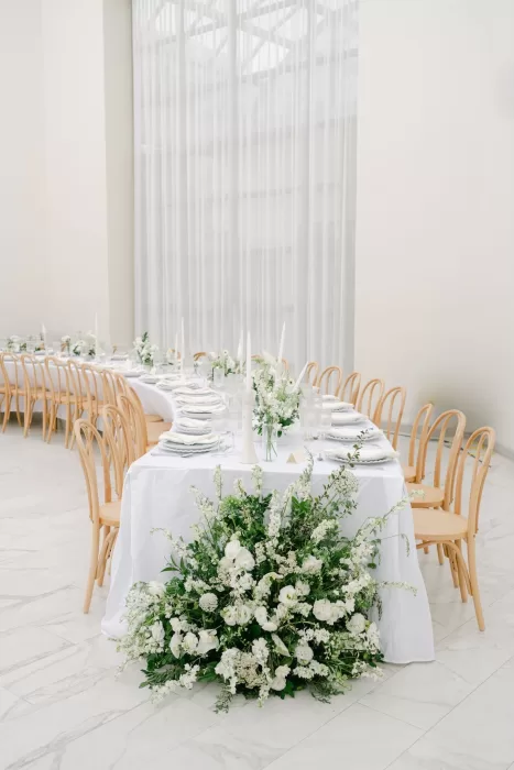Lush floral arrangement at the head of a wedding table inside Luna Escondida’s light-filled venue.