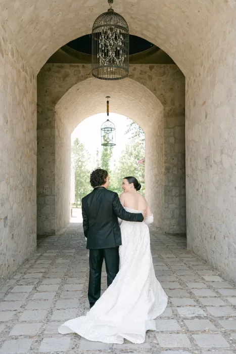 Bride and groom walking under a romantic stone archway at Luna Escondida, sharing a joyful moment