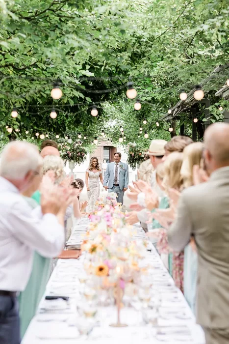 Newlyweds walk into candlelit wedding dinner under tree canopy at Monte Pacis.