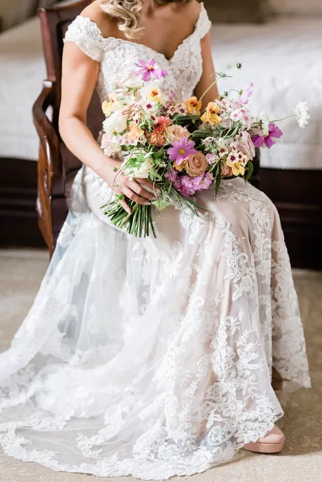 Bride holding colourful summer bouquet in embroidered gown at Monte Pacis