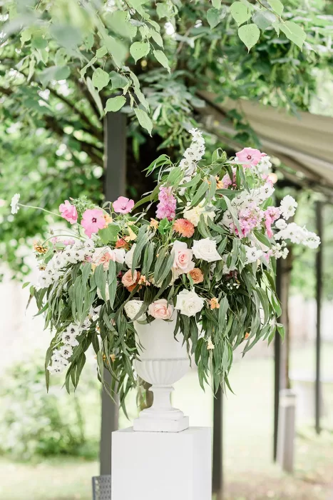Lush outdoor flower arrangement in urn at Monte Pacis wedding ceremony setup