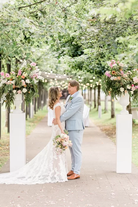Bride and groom in romantic embrace between floral pillars at Monte Pacis