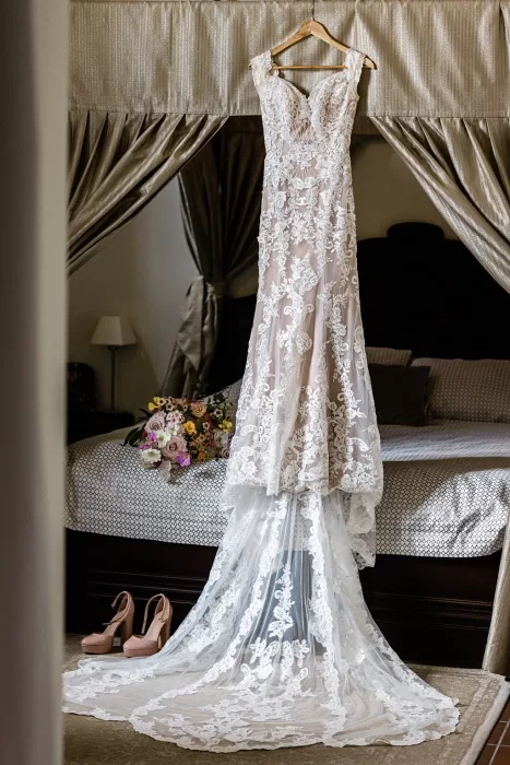 Lace wedding dress with long train hanging in elegant bridal suite at Monte Pacis