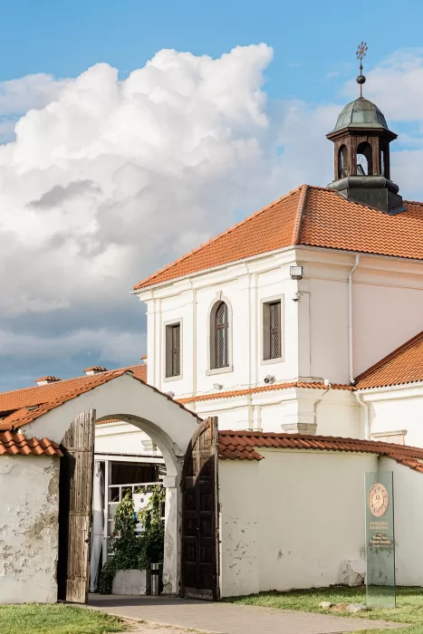 Historic entrance of Monte Pacis with rustic arch and terracotta roof under a bright sky