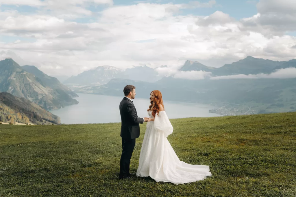 Bride and groom hold hands during their ceremony overlooking Lake Lucerne and the Swiss Alps near Hotel Villa Honegg.