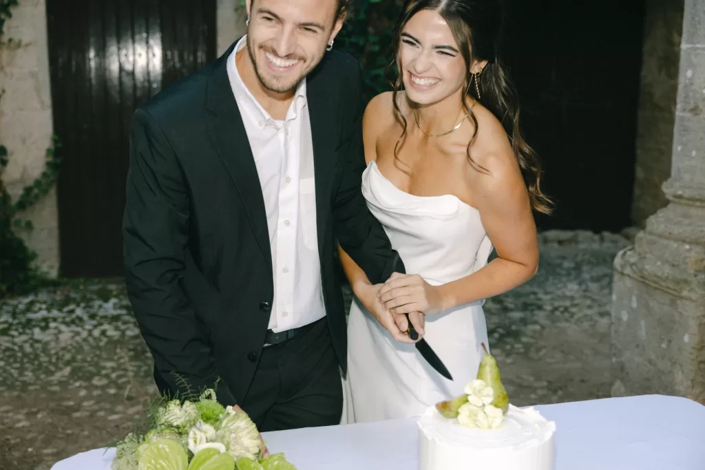 Couple cutting their wedding cake together in the courtyard of Finca Es Convent, captured in a candid moment.