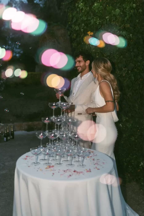 Newlyweds smile beside a champagne coupe tower during the celebration at Finca Son Collell