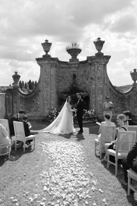 Outdoor ceremony in front of an ornate stone fountain at Villa Medicea di Lilliano, with the couple exchanging vows.