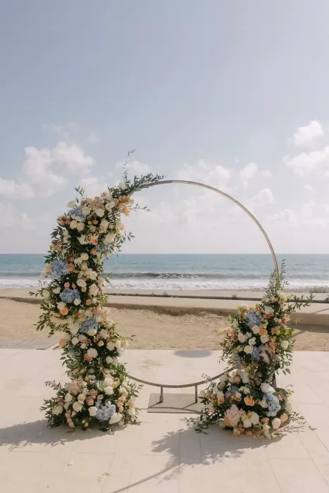 Circular wedding arch adorned with pastel flowers facing the sea at Coral Residences.