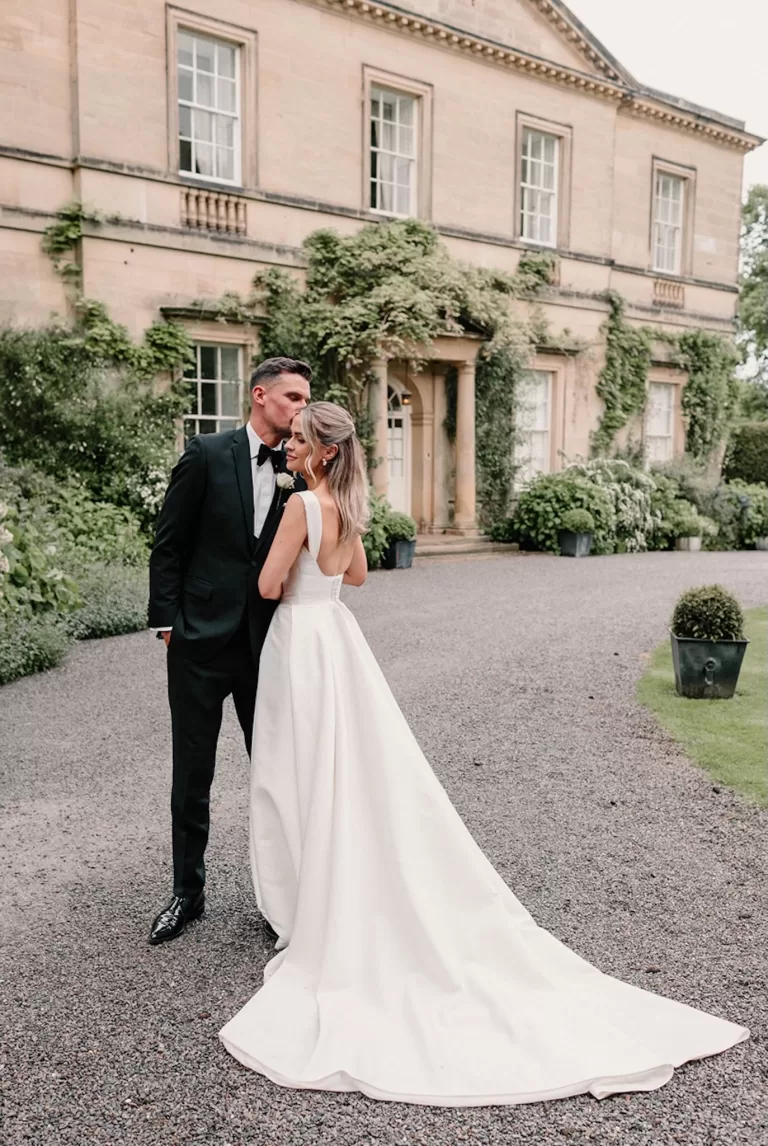 Groom kissing bride’s forehead outside the historic Middleton Lodge mansion.