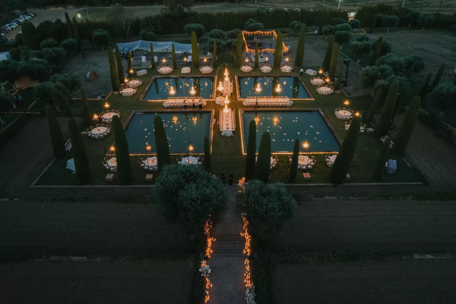 Night aerial view of Mas de Les Voltes wedding dinner with glowing chandeliers and pools.