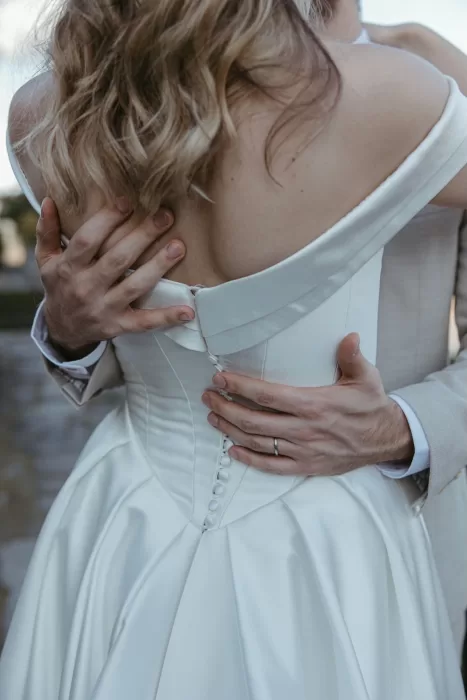 Close-up of groom holding bride in satin wedding gown at Six Senses Douro Valley.