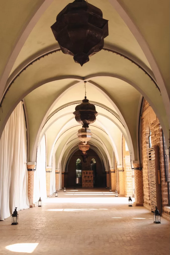 Elegant vaulted hallway with Moroccan lanterns and soft natural light at Beldi Country Club.