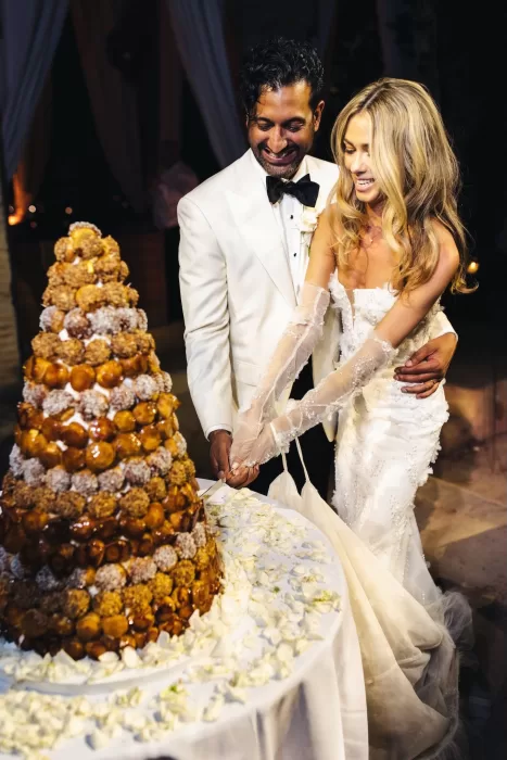 Bride and groom cutting a croquembouche wedding cake together, laughing joyfully at Beldi Country Club.
