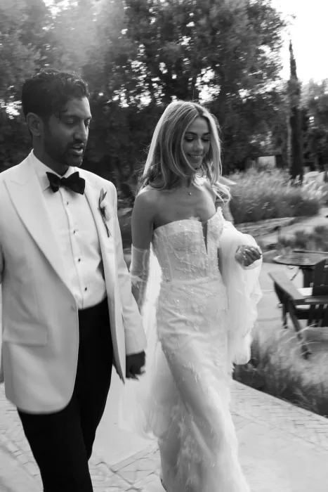 Black and white candid of bride and groom walking outdoors at Beldi Country Club, smiling naturally.