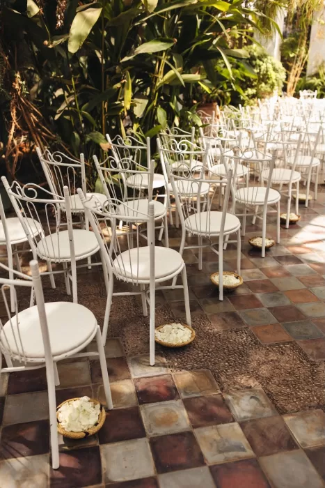 White wrought iron chairs lined with rose petal baskets for a wedding ceremony at Beldi Country Club.