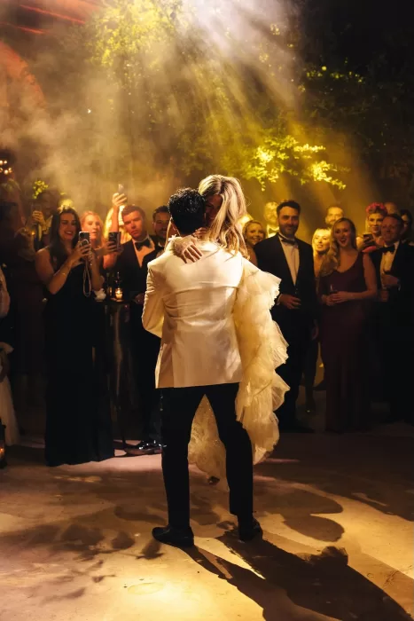Romantic first dance at Beldi Country Club, with the groom lifting the bride under dramatic evening lights and surrounded by guests.