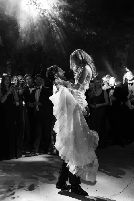 Romantic first dance at Beldi Country Club, with the groom lifting the bride under dramatic evening lights and surrounded by guests.