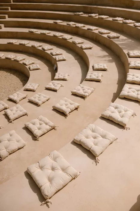 Outdoor amphitheater at Cases de Sa Fonseca prepared for a wedding ceremony with cream cushions on stone steps.