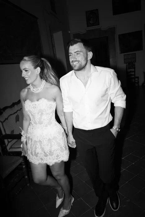 Black and white photo of bride and groom walking hand in hand in evening reception attire at Cases de Sa Fonseca.