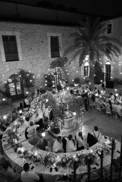 Nighttime wedding dinner at Cases de Sa Fonseca courtyard under string lights and glowing floral tables.
