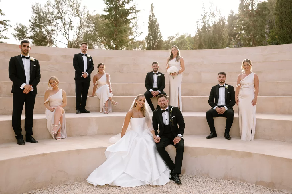 Bride and groom with wedding party at Cases de Sa Fonseca amphitheater, dressed elegantly in black tie and ivory gowns.