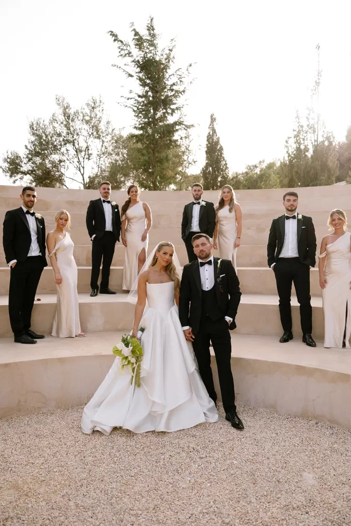 Bride and groom pose with their wedding party on stone steps at Cases de Sa Fonseca.