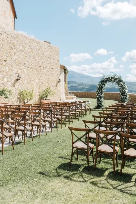 Wedding ceremony setup with floral arch and wooden chairs at Castello di Velona.