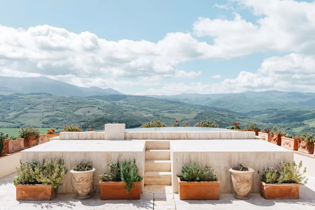 Stone altar at Castello di Velona framed by terracotta planters under blue skies.