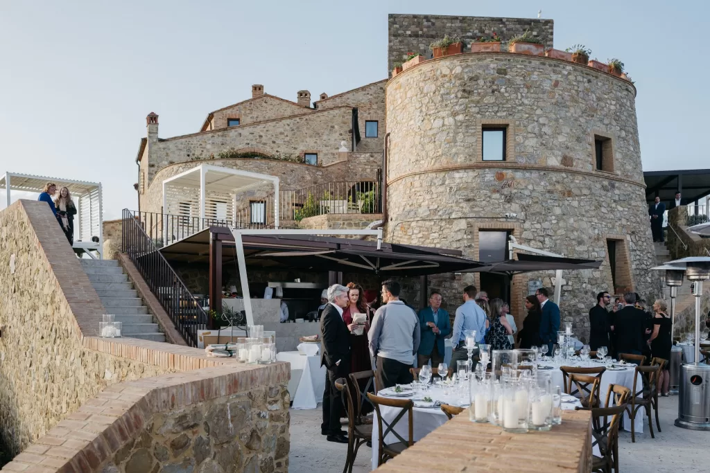 Guests mingling at Castello di Velona courtyard with historic stone walls.