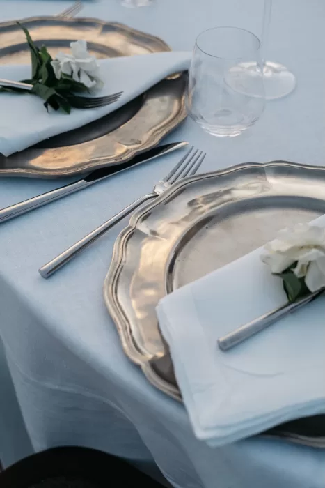 Elegant wedding table setting at Castello di Velona with silver chargers, white napkins, and floral accents.