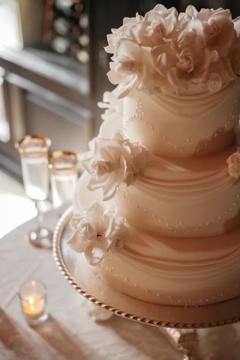 Elegant three-tier wedding cake adorned with white sugar flowers at Castello di Velona.