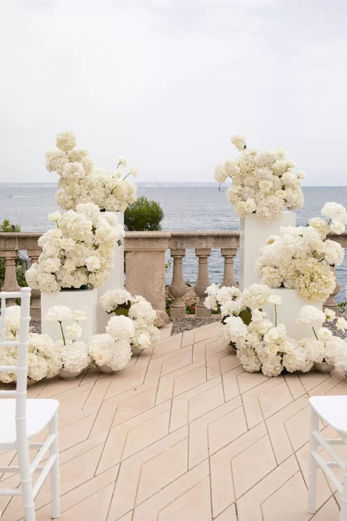 Lush white floral arrangements frame the oceanfront ceremony setting at Hospes Maricel & Spa.