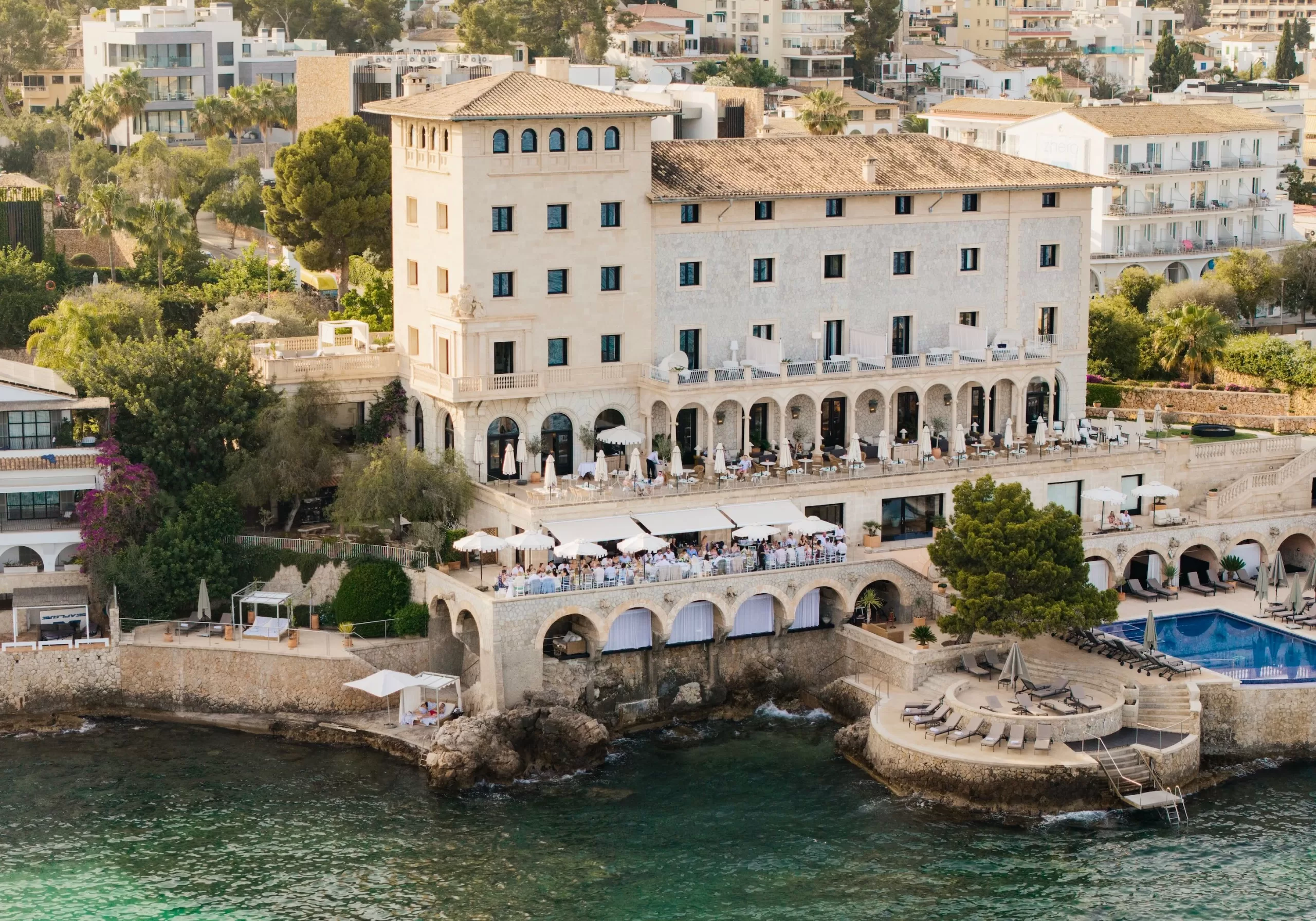 Aerial view of Hospes Maricel & Spa, a historic cliffside hotel overlooking the Mediterranean Sea.