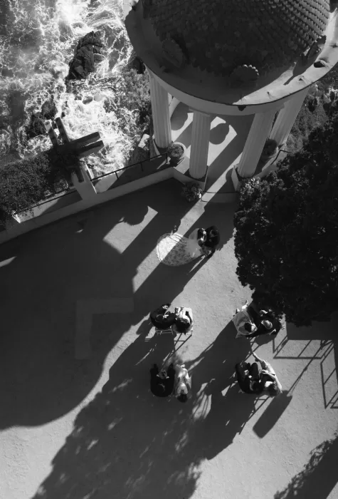 Aerial view of a wedding ceremony beneath the pavilion at Marimurtra Botanical Garden by the crashing waves.